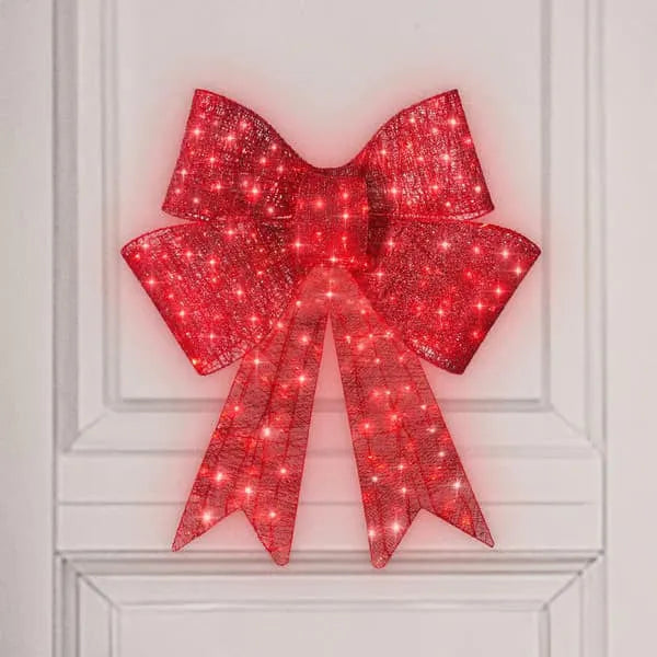 Red satin light up Christmas bowknot on a tree branch with warm glow