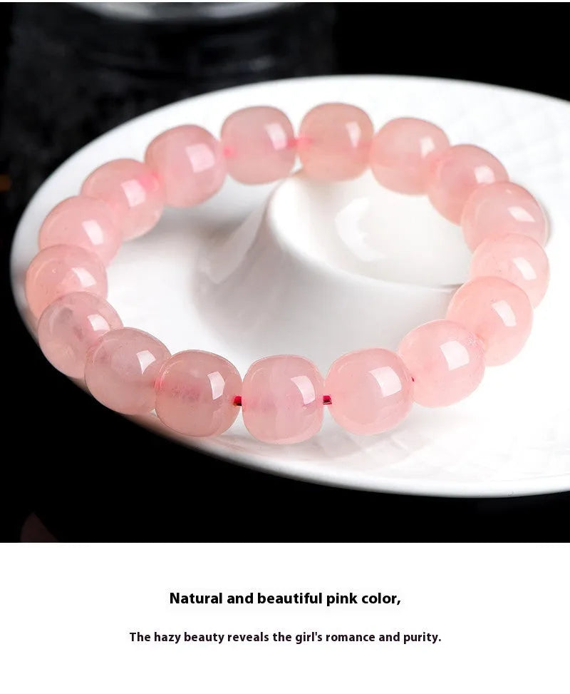 Natural pink crystal barrel bead bracelet with geometric design on a wrist.
