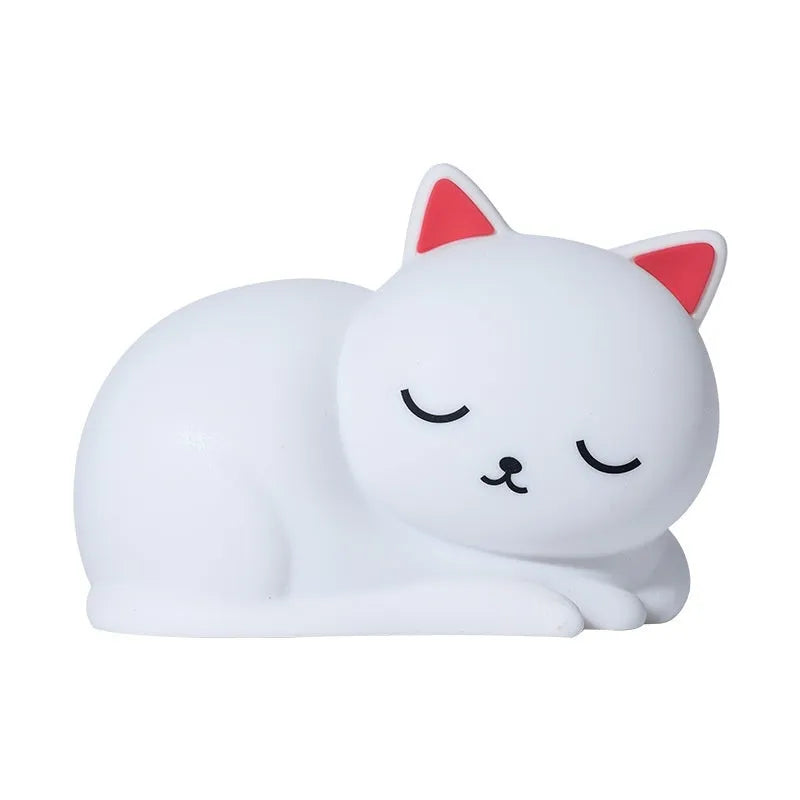 Sleepy cat shaped silicone induction night light with white glow on table