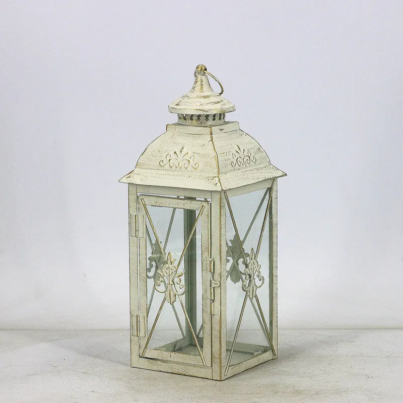 Black wrought iron floor-standing storm lantern with clear tempered glass panels on a garden patio.