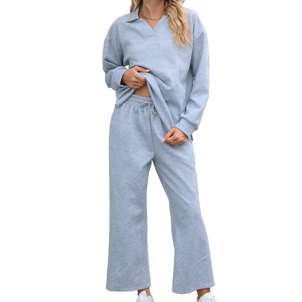 Women's black knitted jacquard suit with lapel sweater and elastic waist cropped pants on a hanger.