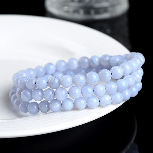 Blue agate bracelet with striped beads and a Ruyi charm on a wrist.