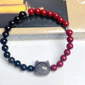 Obsidian crystal cat bracelet with colourful woven string band on a wrist.