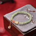 Natural jade bead bracelet with a gold-plated gourd charm and fu character.