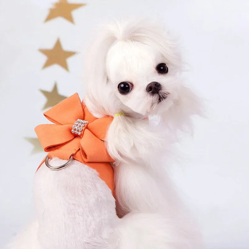A pink dog harness with a white bow knot on an adjustable microfiber chest strap.