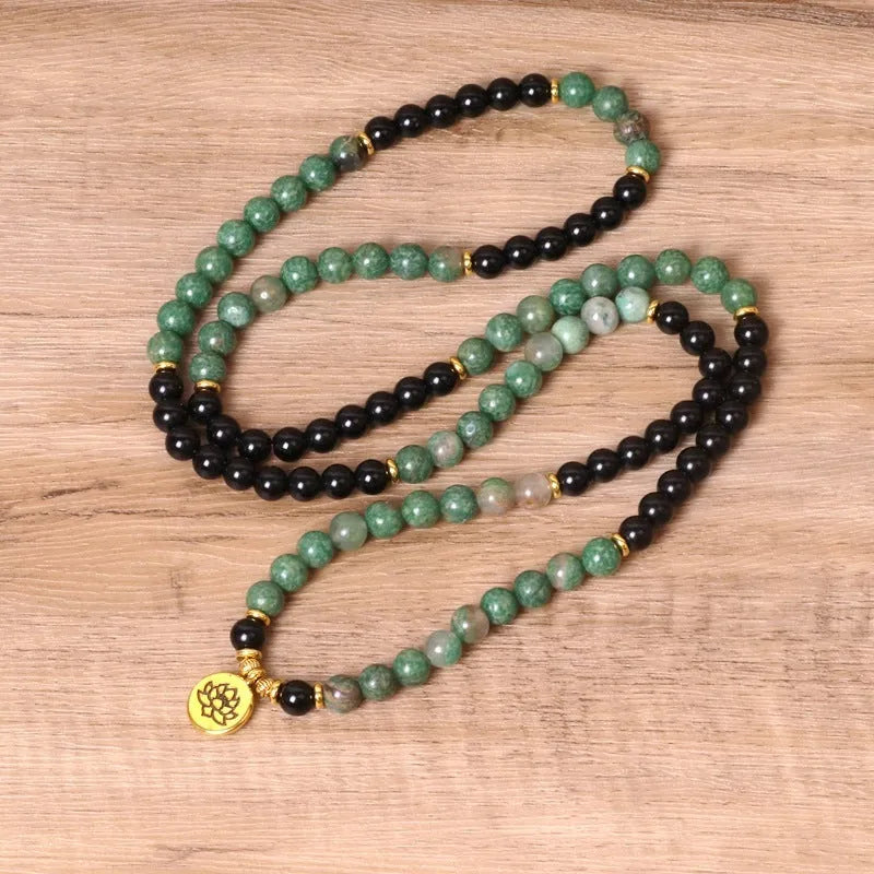 Green and black alloy bead long bracelet with elasticated band on a wrist.