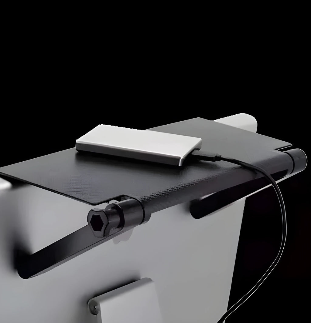 Black adjustable screen top shelf on a desktop monitor holding a streaming device and remote