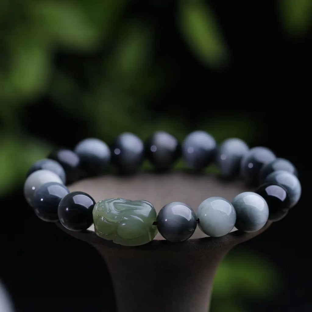 Black bracelet with 10mm Eagle Eye stone beads and a Hetian Jade Pixiu charm.