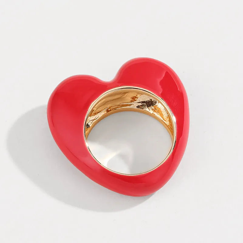 Colourful three-dimensional heart-shaped enamel ring in zinc alloy on a hand.