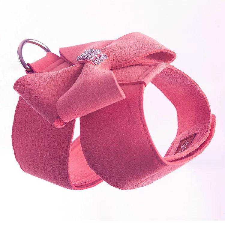 A pink dog harness with a white bow knot on an adjustable microfiber chest strap.