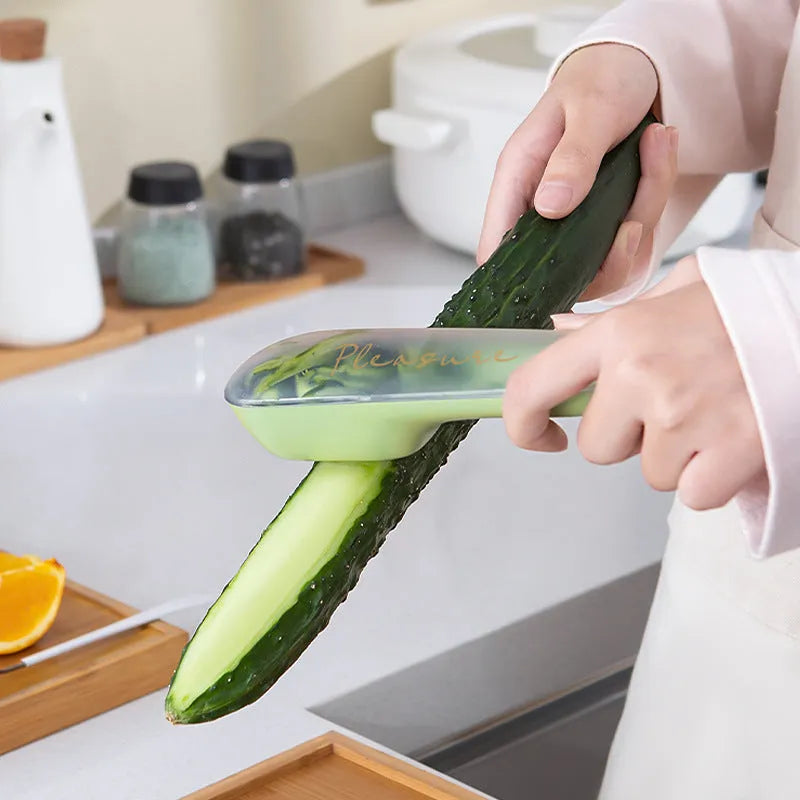 Dark green kitchen peeler with storage tube and stainless steel blade on a kitchen counter.
