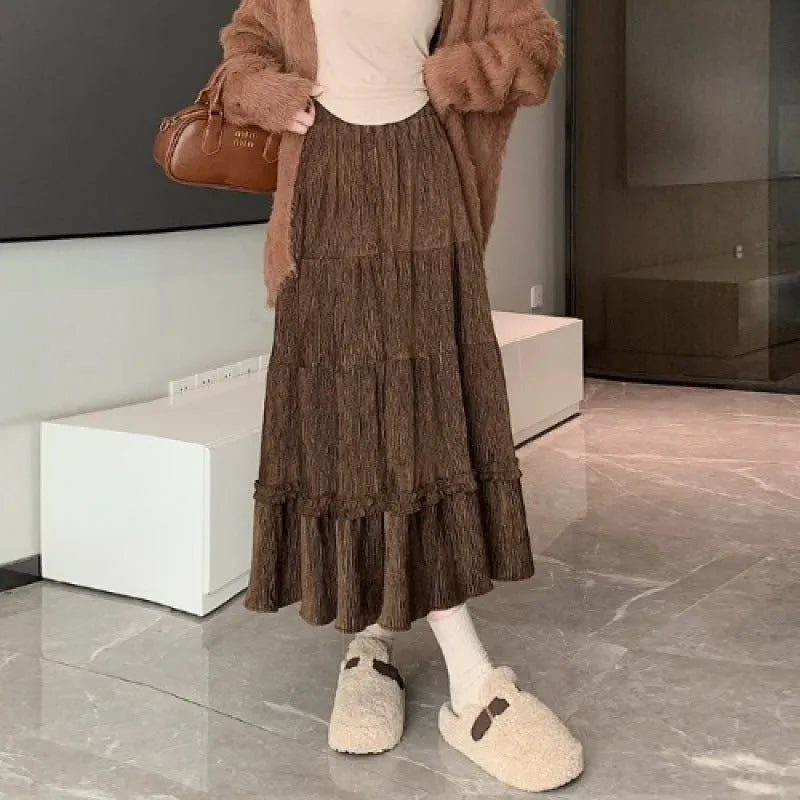 A woman modelling a beige corduroy midi A-line skirt with an elasticated waistband.
