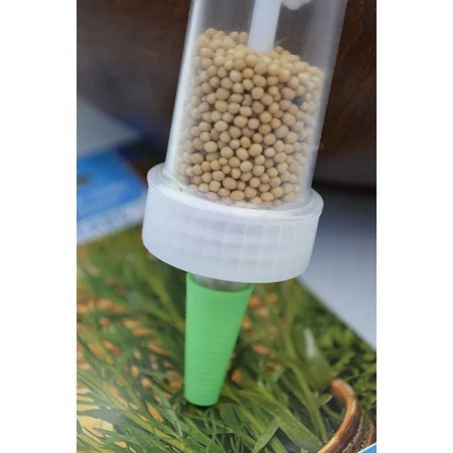 A white plastic mini garden seeder tool, 12cm long, for planting seeds in pots and trays.