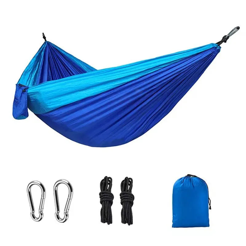 Sapphire blue parachute nylon hammock hung between trees, showing its full 270cm length and woven texture.