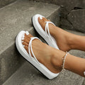 A pair of thick-soled, herringbone-pattern flip-flops on a sandy beach.