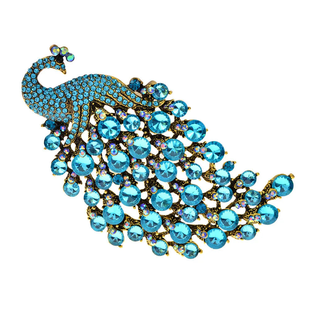 Colourful metal peacock brooch in red, green, and blue with rhinestone accents on a white background