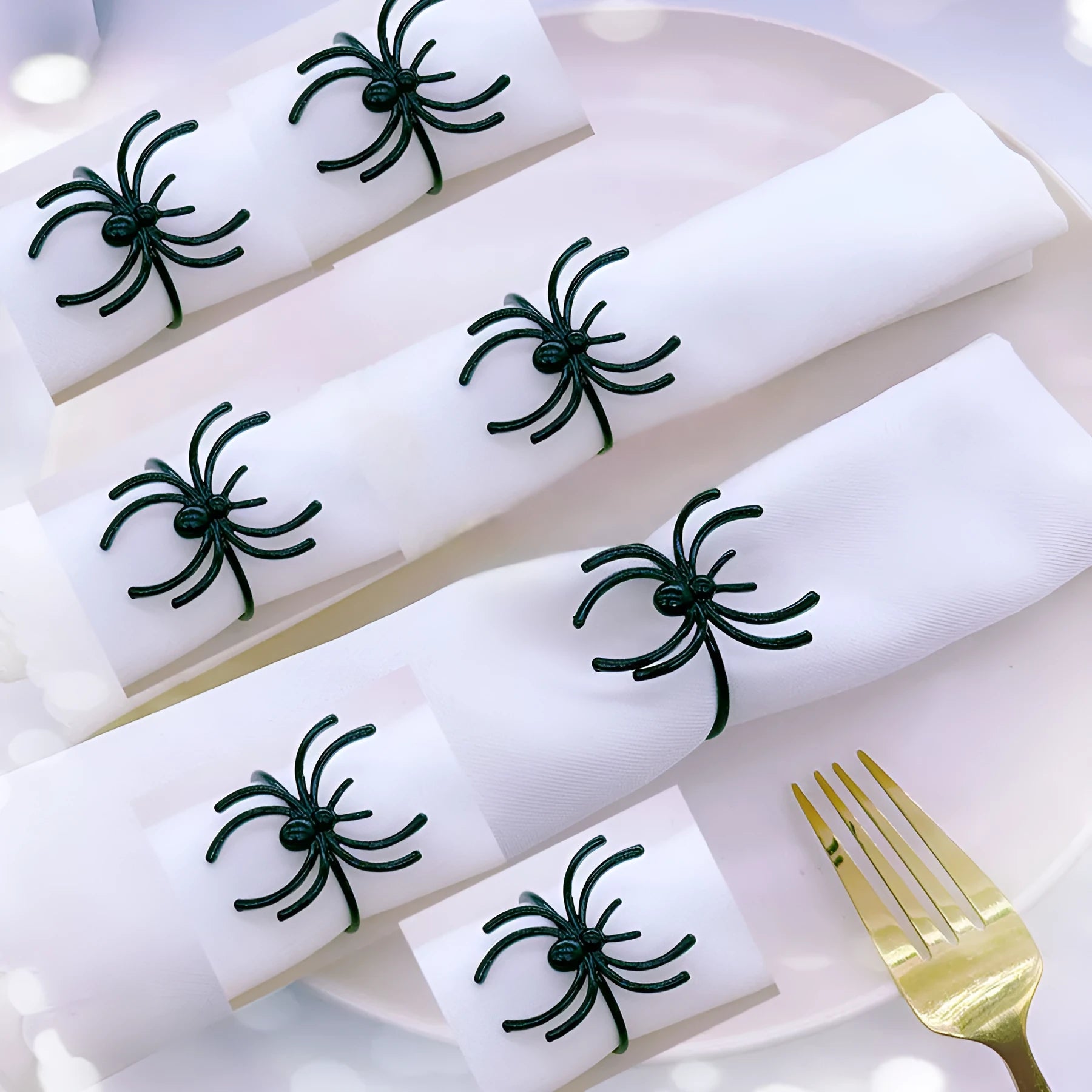 Set of six black alloy Halloween napkin rings with detailed spider design on a table setting.