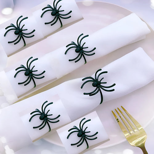 Set of six black alloy Halloween napkin rings with detailed spider design on a table setting.