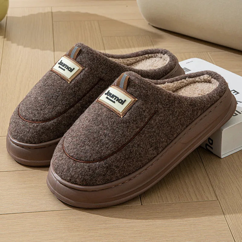 Men's brown suede slippers with a thick, textured sole on a wooden floor