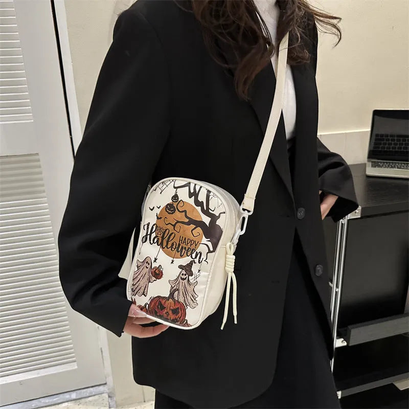 Black Halloween graffiti crossbody bag with cartoon pumpkin, ghost, and bat print, shown with adjustable strap.