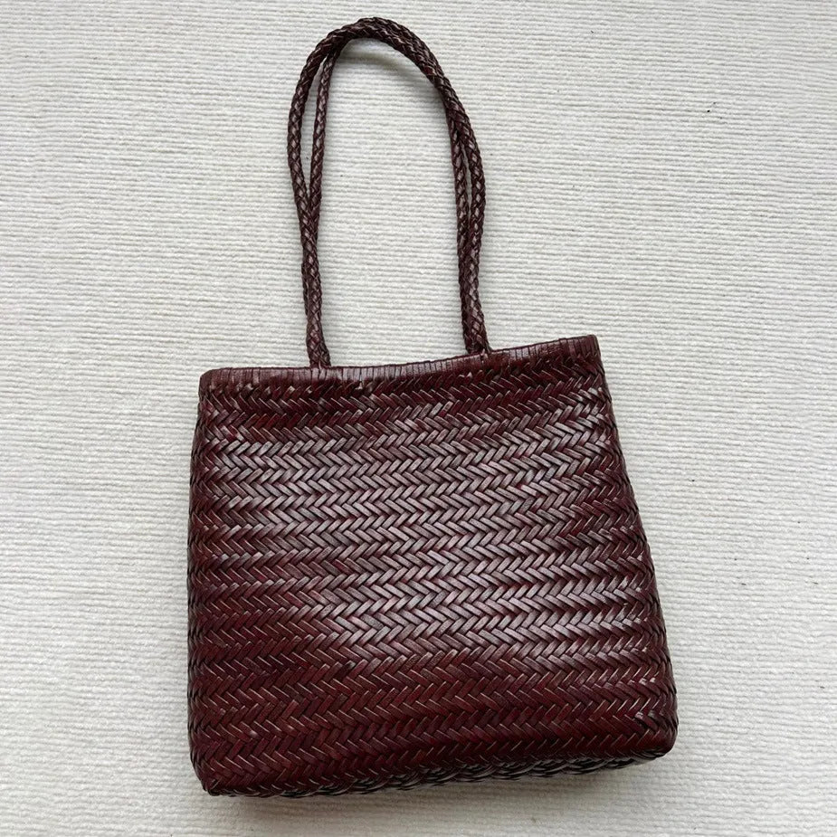 Brown handmade woven leather tote bag with a three-dimensional front pocket and shoulder strap.