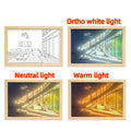 LED illuminated decorative picture light on a bedside table showing a sunny landscape scene.