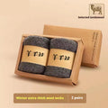 Pair of thick grey winter wool socks with a cushioned merino midsole, folded next to their presentation box.