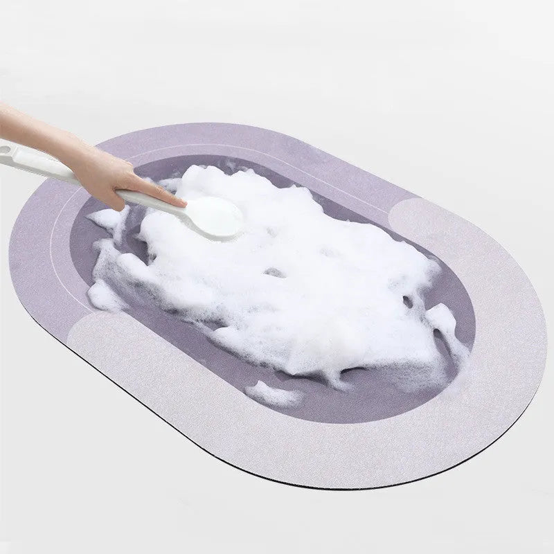 Oval grey polyester door mat with textured rubber non-slip backing on a wooden floor.