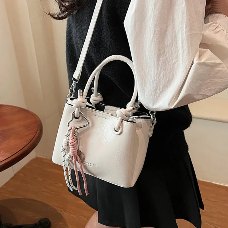Women's PU one-shoulder bucket messenger bag in black with pendant, showing front view with single strap