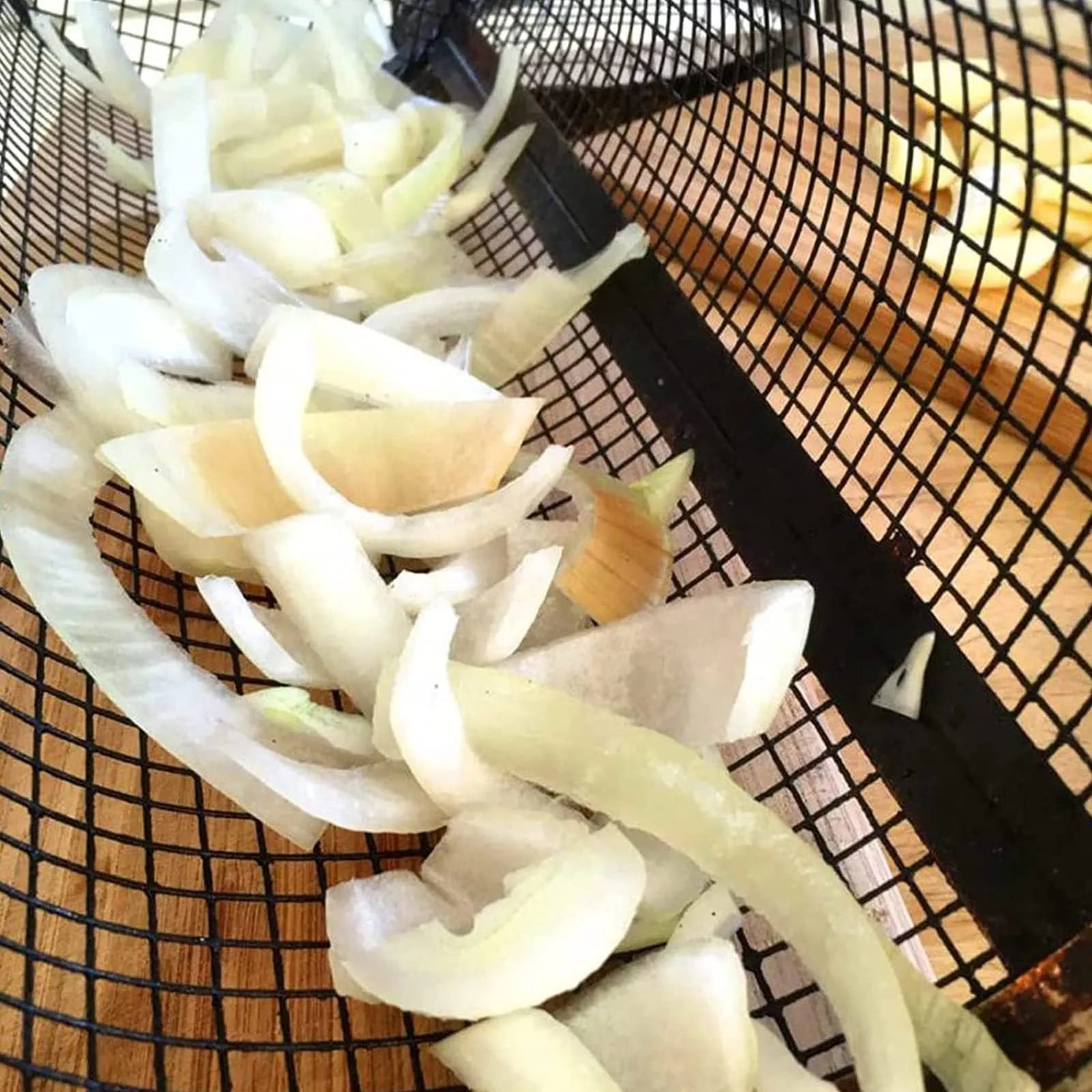 A cylindrical iron wire mesh rolling barbecue basket with a metal hook for handling.