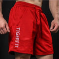 Man wearing grey loose-fit mesh running shorts made from quick-dry polyester fabric.