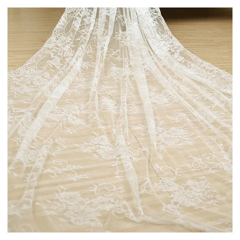 White embroidered lace tablecloth made from nylon yarn, 150x300cm, laid flat on a table with decorative pattern visible.