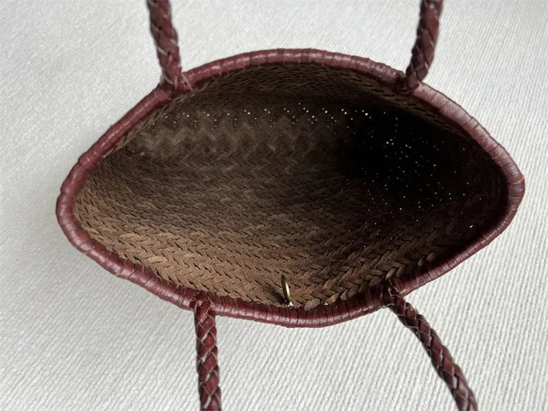 Brown handmade woven leather tote bag with a three-dimensional front pocket and shoulder strap.