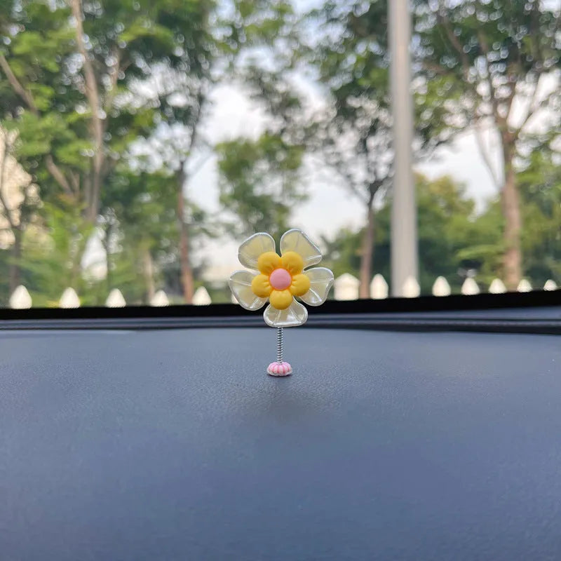 Small colourful plastic swing car decoration hanging from a rear-view mirror, showing blue, green, pink, purple, and yellow colour options.