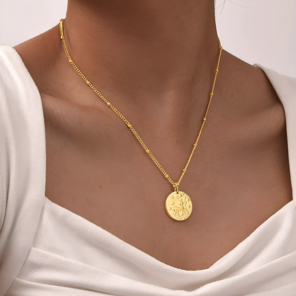 Stainless steel cross chain necklace with a geometric round bead pendant embossed with a zodiac constellation design.