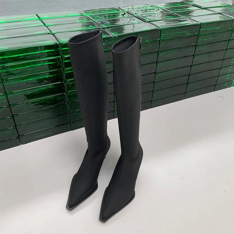 Women's black pointed toe below-the-knee boots with a stiletto heel and back zip on a neutral background.