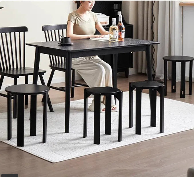 Stackable round iron dining stool in smoked black, walnut, cherrywood, or cream colour on a tiled floor.