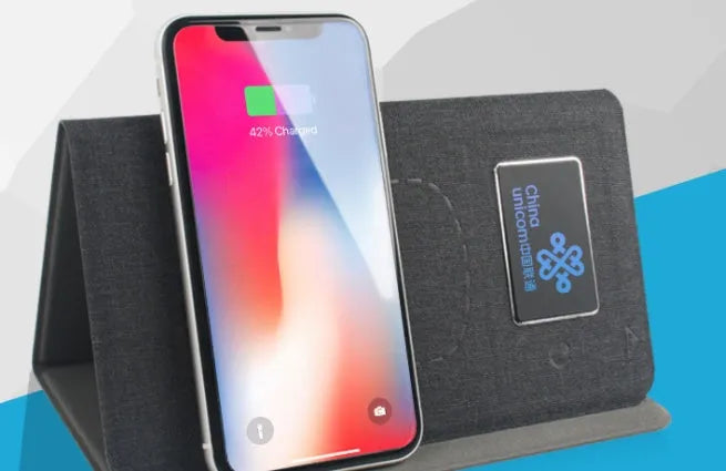 Folding wireless charging mouse pad set with compact wireless mouse on branded cloth surface.