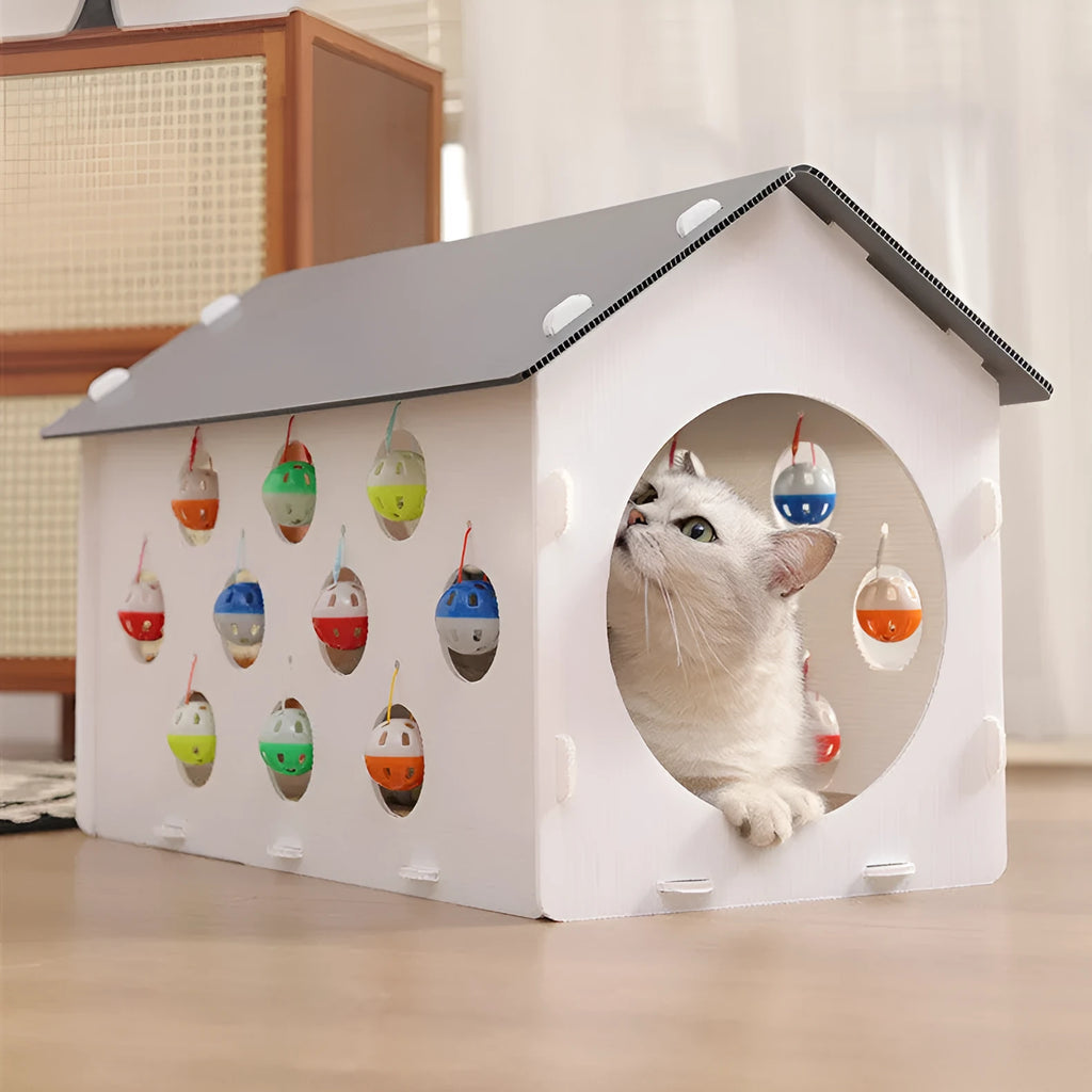White plastic house-shaped cat scratch board with an integrated nest and a red bell ball toy inside.