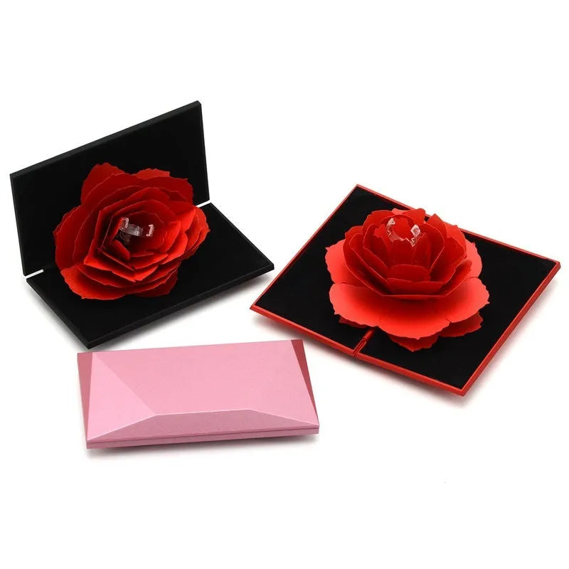 Red heart-shaped rotating ring box with 3D white rose decoration on top.