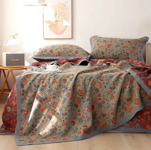 Three-piece cotton gauze bed set with floral plants and flowers pattern, showing blanket and pillowcases.