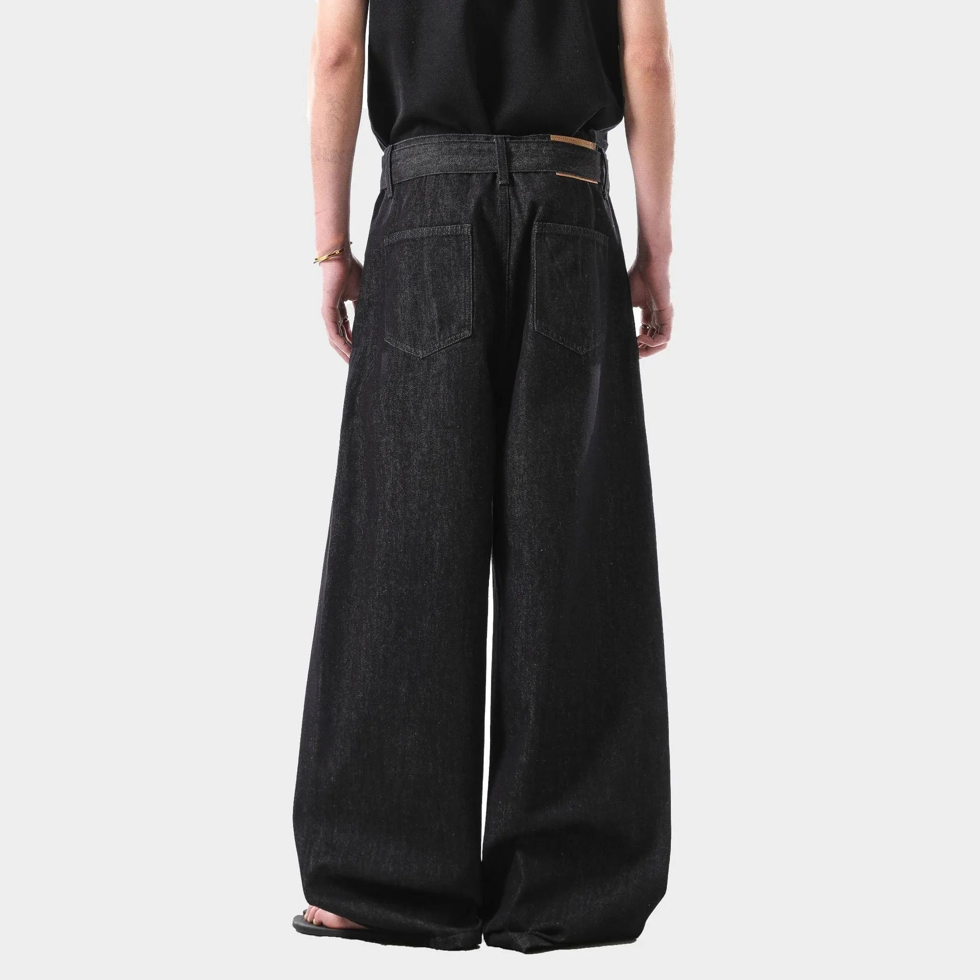 Black high-waist straight-leg jeans with gold contrast stitching on a flat lay.