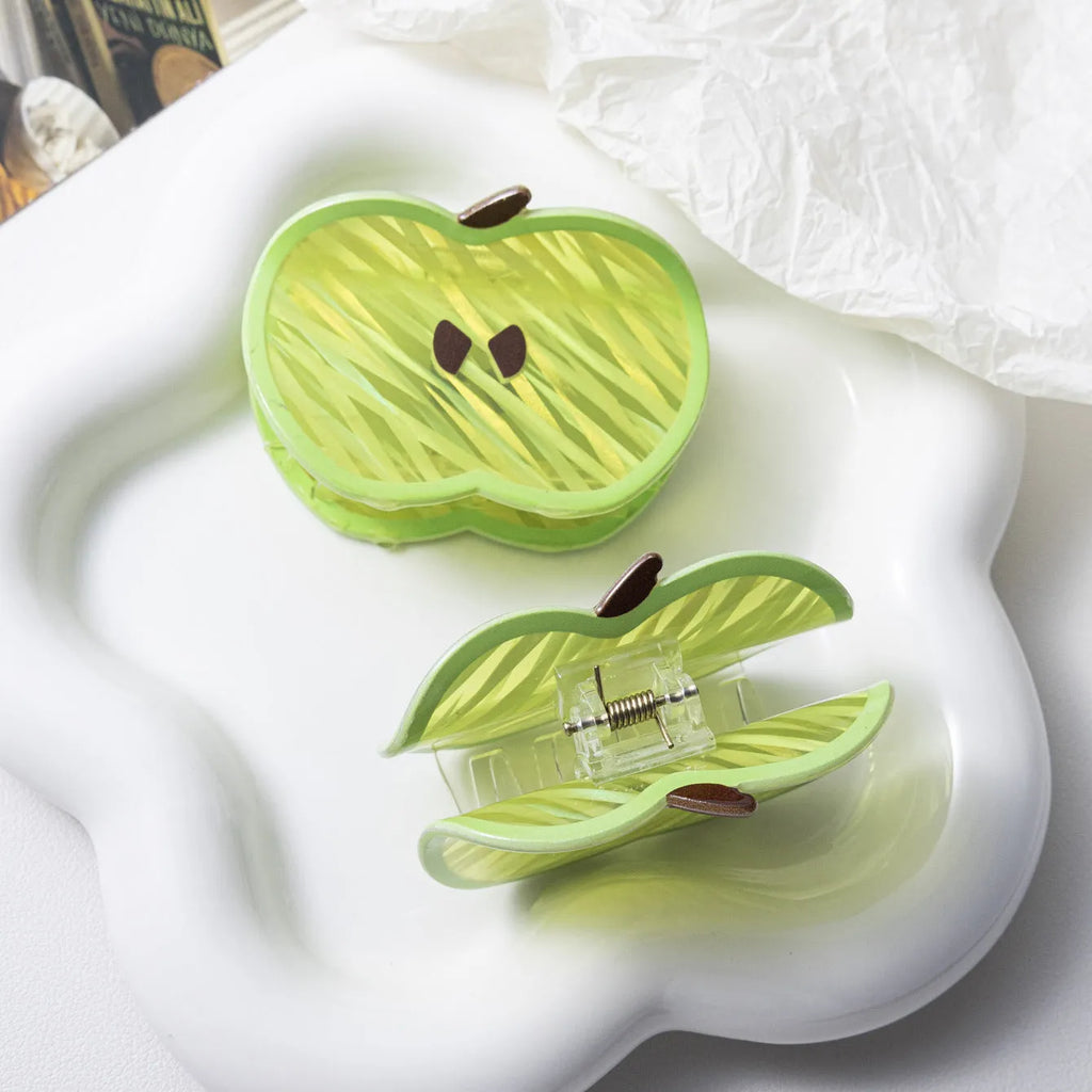 Green apple-shaped claw clip with polished PVC finish, 7.5cm long, on a plain background