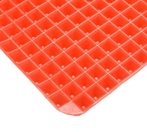 Red silicone pyramid grid cooking mat on a kitchen countertop.
