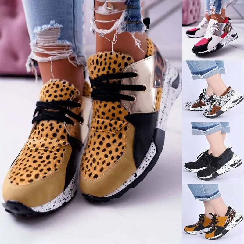 Women's black suede wedge sneakers with a round toe and low-cut design on a wooden floor.