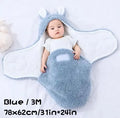 Baby wearing a blue adjustable cotton sleep sack with velcro swaddle closures and a head-protecting hood.