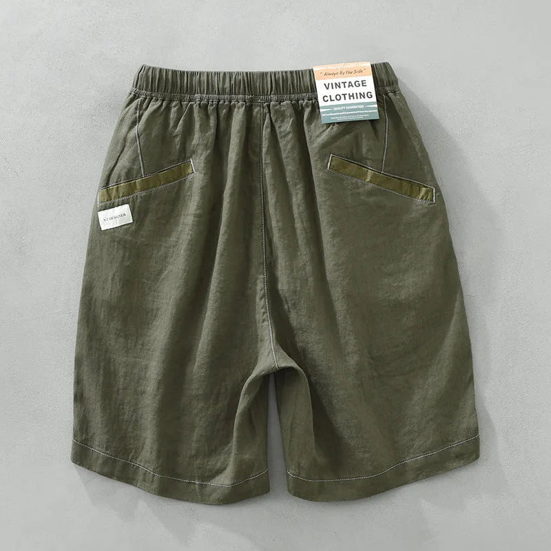 Men's loose fit linen shorts in green on a hanger, showing straight leg and drawstring waist.