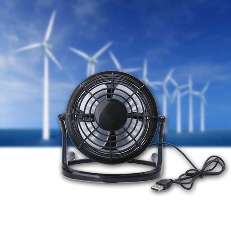 Mini black USB desk fan with adjustable head on a desk next to a laptop.