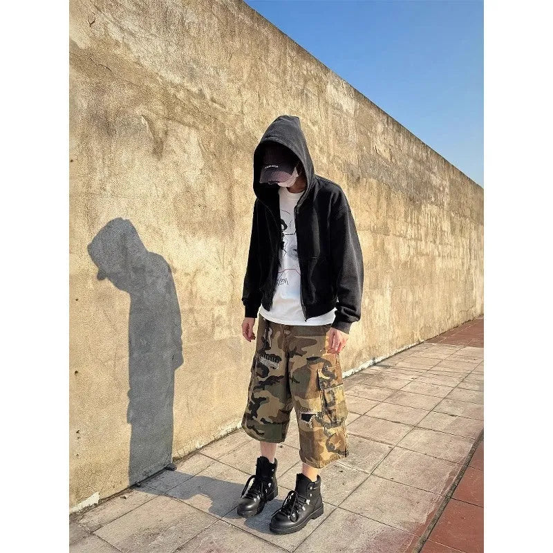 Men's loose-fit camouflage cropped jeans with ripped details and patches on a straight leg.