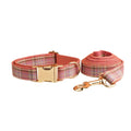 Plaid pattern dog collar and leash set with red bow tie accessory on cloth fabric